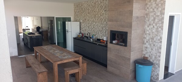 A modern kitchen with a wooden dining table, a built-in stove, and a small fireplace.