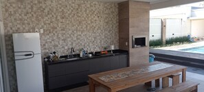 A modern kitchen with a built-in refrigerator, dark cabinetry, and a wooden table with a tile design.