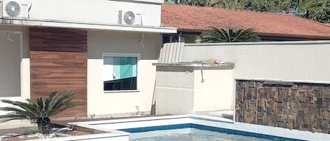 A modern house with a swimming pool, a wooden deck, and a stone wall.