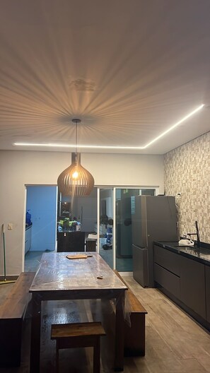 A modern kitchen with a central island, a hanging light fixture, and a refrigerator.