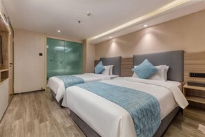 A hotel room with two beds, a glass shower enclosure, and a wooden floor.