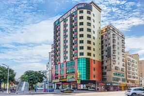 A multi-story hotel with a prominent corner location, featuring a mix of commercial spaces on the ground floor and residential units above. - Nanfang Yijing Hotel (Shenzhen Baoan International Airport Gushu Subway Station store) (Shenzhen)