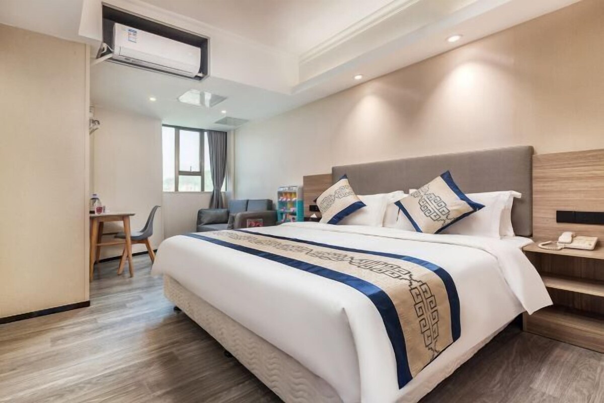 A hotel room with a bed, bedside table, and a desk with a chair.