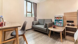 A room with a sofa, a small table, a vending machine, and a shelf with items. - Nanfang Yijing Hotel (Shenzhen Baoan International Airport Gushu Subway Station store) (Shenzhen)