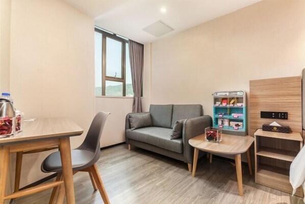 A room with a sofa, a small table, a vending machine, and a shelf with items.