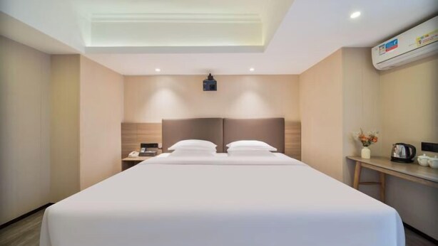 A hotel room with a large bed, bedside tables, a desk, and an air conditioning unit. - Nanfang Yijing Hotel (Shenzhen Baoan International Airport Gushu Subway Station store) (Shenzhen)