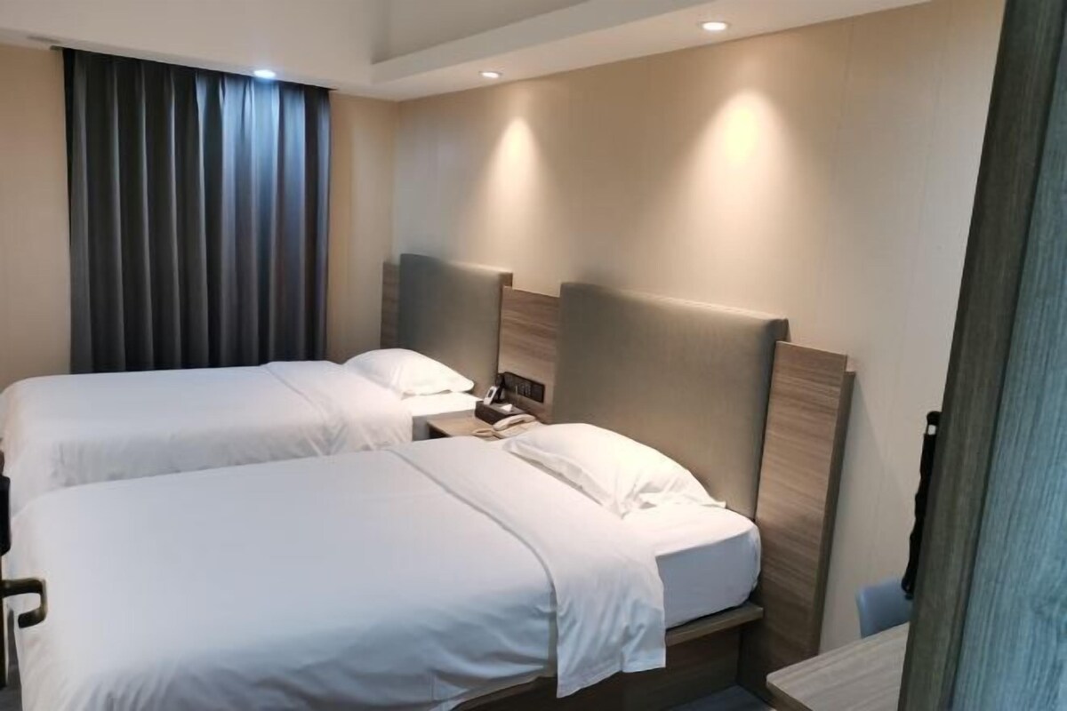 A hotel room with two beds, a nightstand, a telephone, and a curtain.