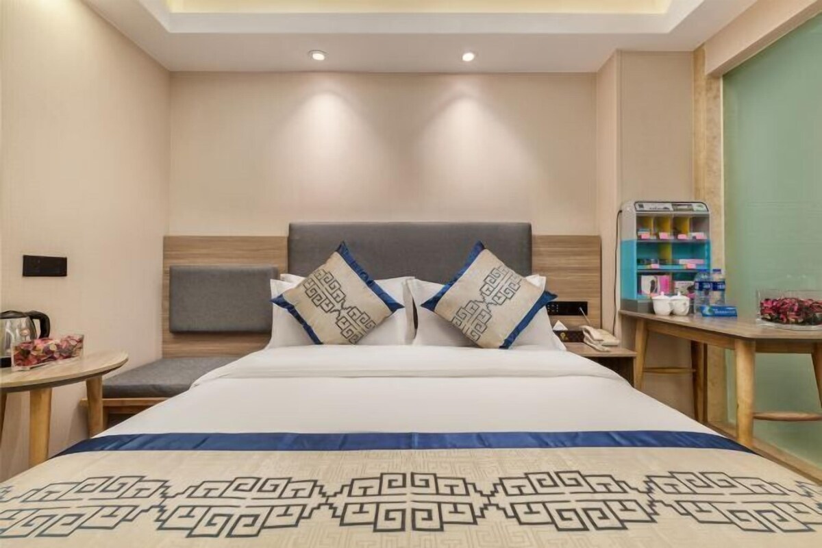 A hotel room with a large bed, two bedside tables, a small desk, and a minibar.