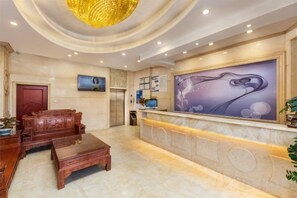A hotel lobby with a reception desk, seating area, and a large abstract painting. - Nanfang Yijing Hotel (Shenzhen Baoan International Airport Gushu Subway Station store) (Shenzhen)