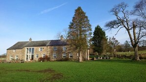 Um edifício de pedra com várias janelas e um grande gramado frontal.