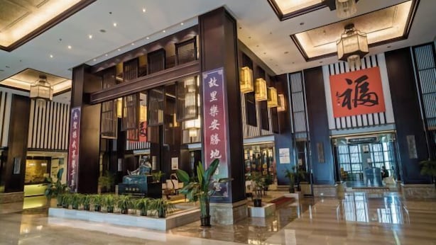 A spacious lobby with a modern design, featuring a reception desk, potted plants, and a large illuminated sign. - Sunwu Hot Spring International Hotel (Huimin)