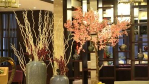 A room with a dining table, chairs, and two vases with branches and flowers. - Sunwu Hot Spring International Hotel (Huimin)