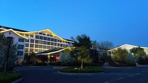 A modern hotel with a multi-story structure, a landscaped entrance, and a well-lit facade. - Sunwu Hot Spring International Hotel (Huimin)