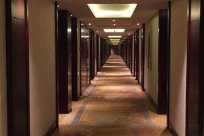 A hotel corridor with a carpeted floor, doors on both sides, and recessed lighting. - Sunwu Hot Spring International Hotel (Huimin)