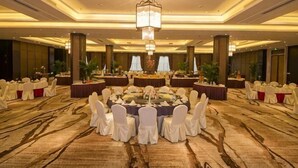 A banquet hall with round tables, white chairs, and a central stage. - Sunwu Hot Spring International Hotel (Huimin)