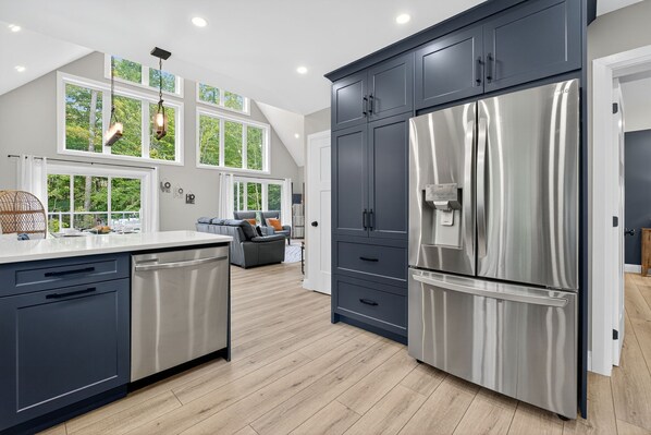 A modern kitchen with dark cabinets, stainless steel appliances, and a large island. - Sleeps-8, Hot Tub, Sauna, EV Charger (Haliburton)