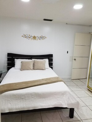 Relax in a serene space with a neatly made bed, a white wardrobe, and a small glass table.
