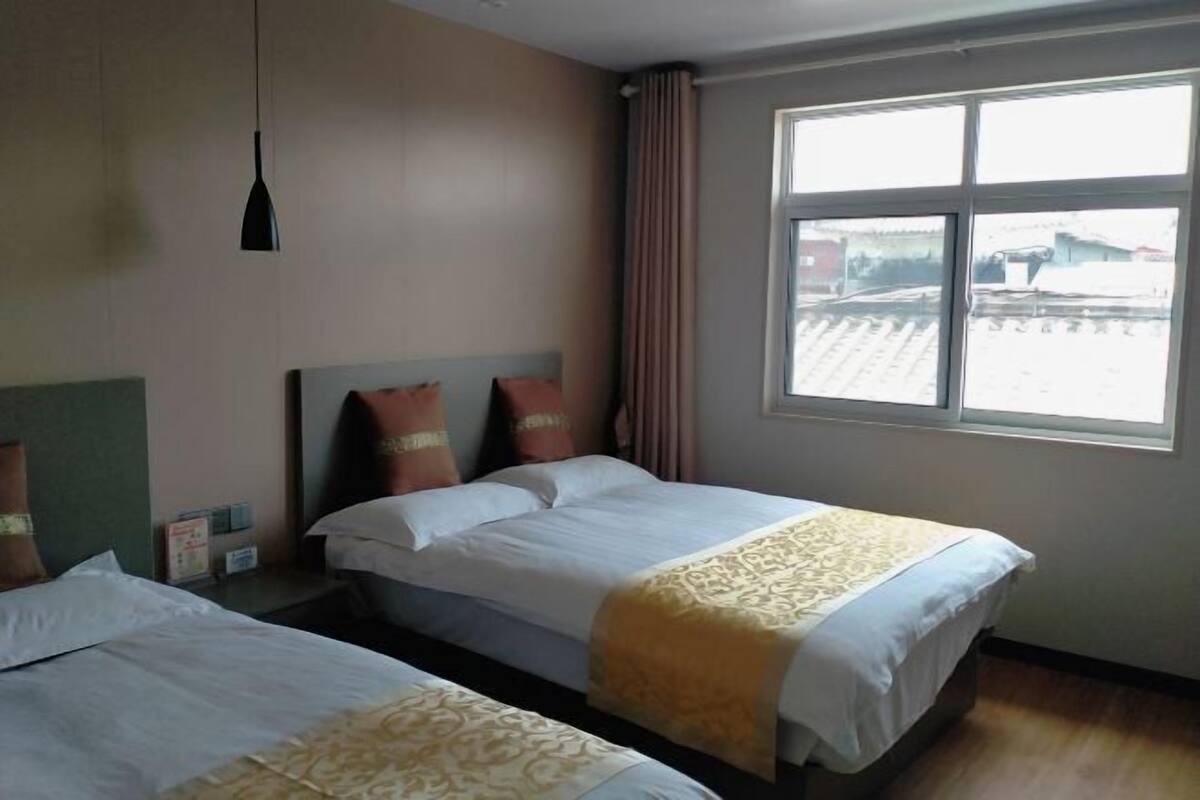 A hotel room with two beds, a window with a view, and a hanging light fixture.