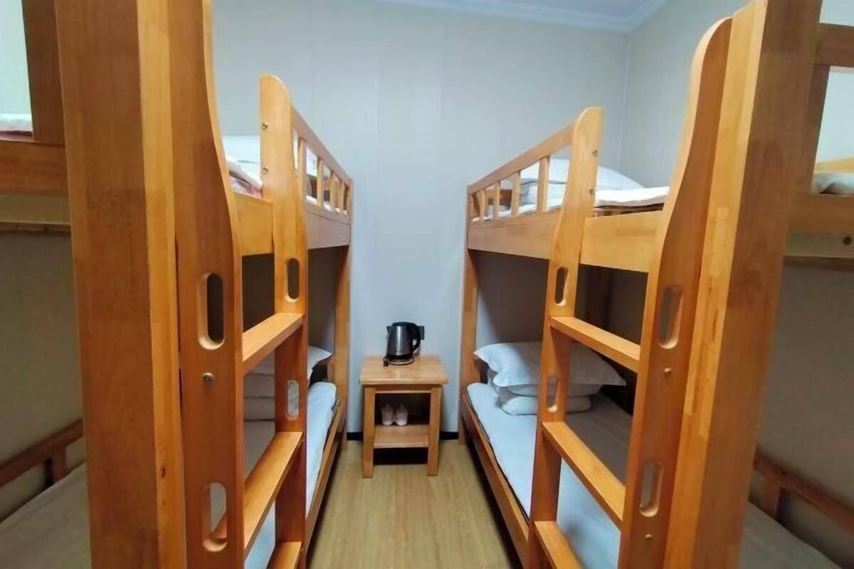 A small, compact room with two wooden bunk beds and a small table with a kettle.