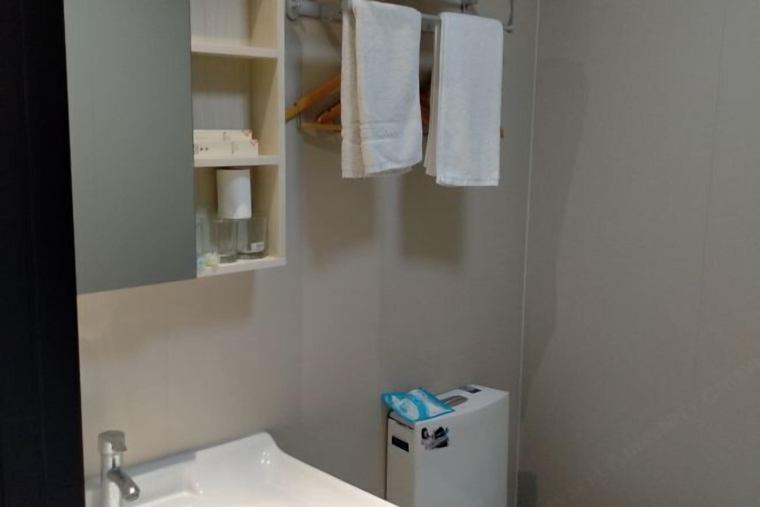 Ein Badezimmer mit Waschbecken, Handtuchhalter und Toilettenpapierhalter.