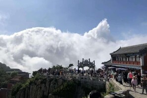 A traditional building with a prominent entrance, a stone bridge, and a crowd of people. - Xianju Hotel (Tai'an)