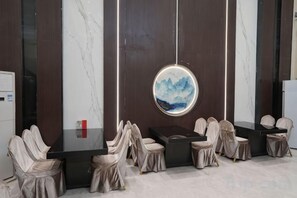 A conference room with a round table, chairs, and a wall-mounted painting. - Xianju Hotel (Tai'an)