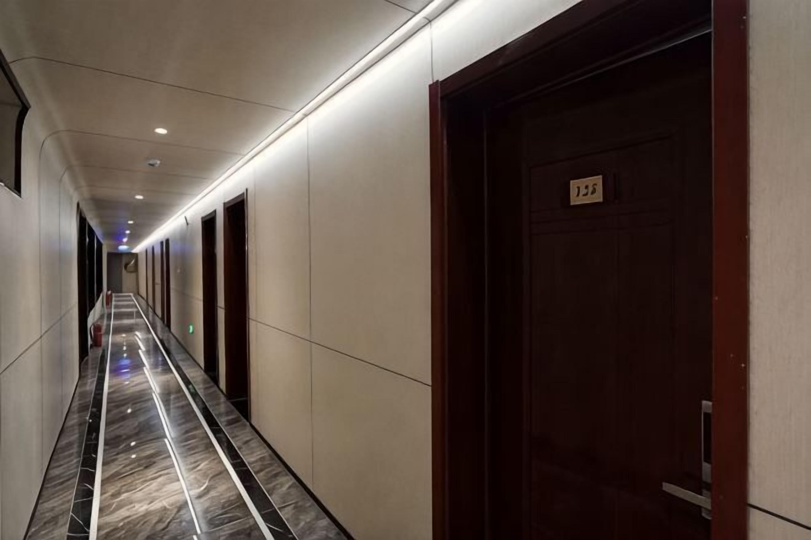 Um corredor de hotel com portas, piso de mármore e uma placa na parede.