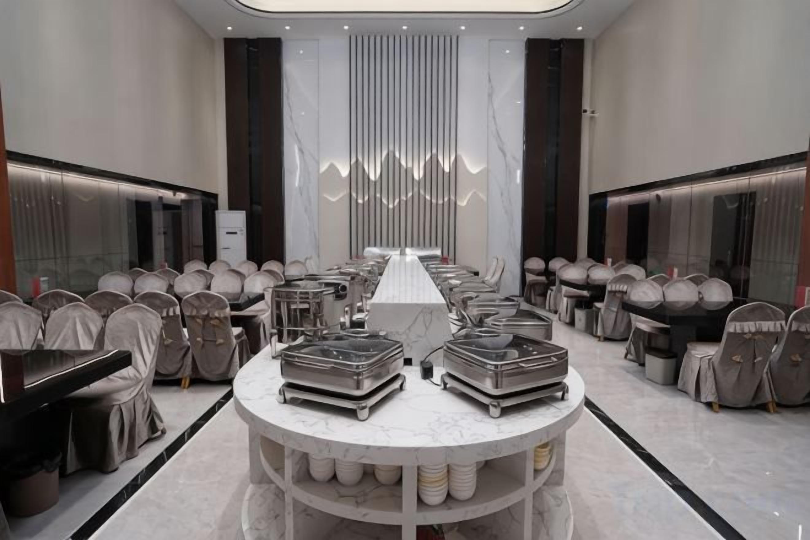 A conference room with a long table, chairs, and buffet stations.