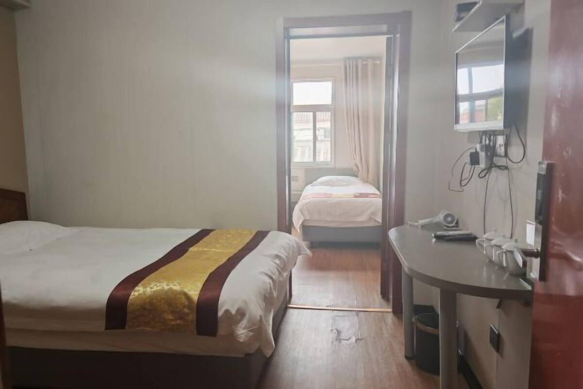 A hotel room with two beds, a desk, a mirror, and a window.
