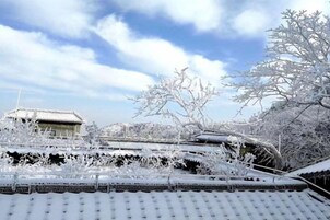 A traditional building with a tiled roof, surrounded by snow-covered trees and structures.