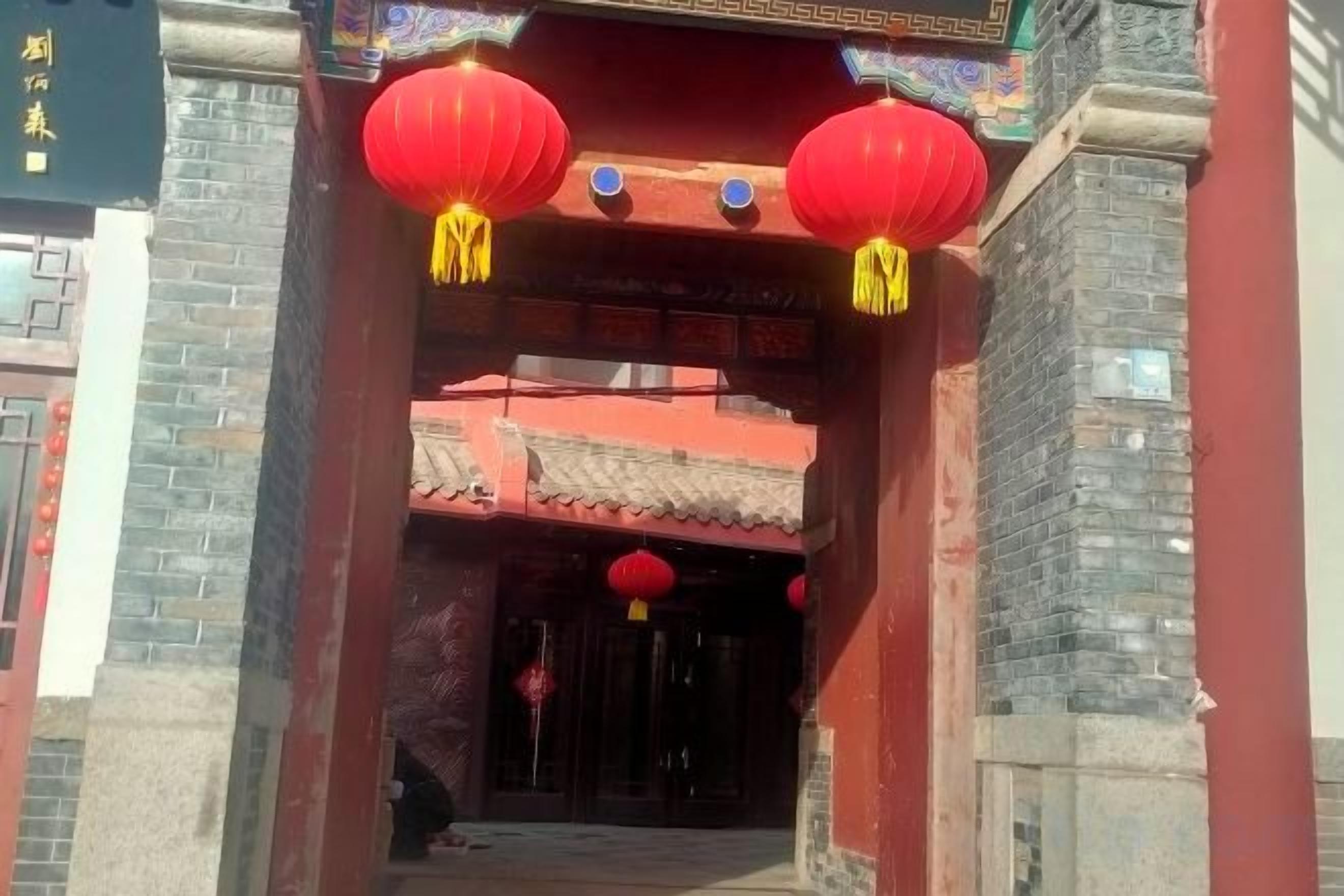 Entrada de un edificio chino tradicional con faroles rojos y tejado de tejas.
