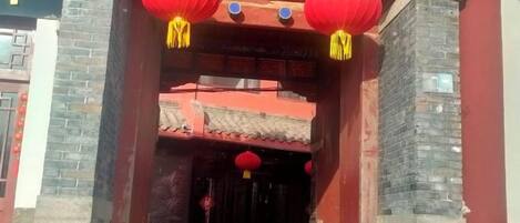 Entrada de un edificio chino tradicional con faroles rojos y tejado de tejas.