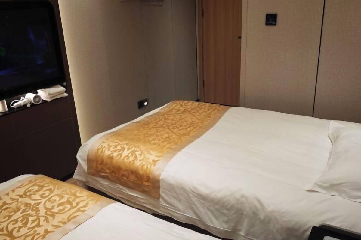 A hotel room with a bed, a TV, and a small table with a remote control.