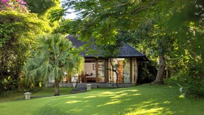A house with a tiled roof, surrounded by lush greenery and a well-maintained lawn. - Villa Amita by Nakula (Kerobokan)