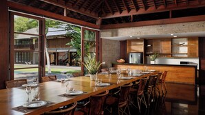 A spacious dining area with a long wooden table set for a meal, surrounded by wicker chairs. - Villa Amita by Nakula (Kerobokan)