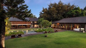 A modern outdoor area with a swimming pool, lounge chairs, and a wooden deck. - Villa Amita by Nakula (Kerobokan)