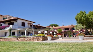 Eine Villa mit Mauerwerk, Sitzgelegenheiten im Freien und Blumentöpfen.