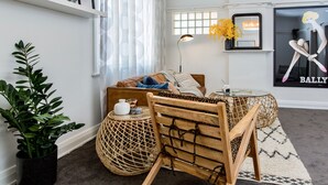 Ein gemütliches Wohnzimmer mit einer Couch, einem Holzstuhl, einem runden Tisch und einem Topf mit Pflanze.