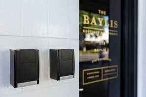 A door with two black intercom devices and a glass panel displaying the name "The Baylis" and some text.