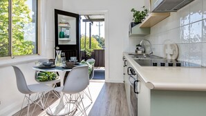 Eine moderne Küche mit weißen Schränken, einem eingebauten Herd und einem Fenster mit Blick auf einen Garten.