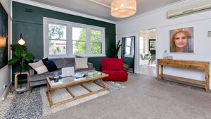 Ein Wohnzimmer mit grauem Sofa, rotem Sessel und Couchtisch aus Holz.