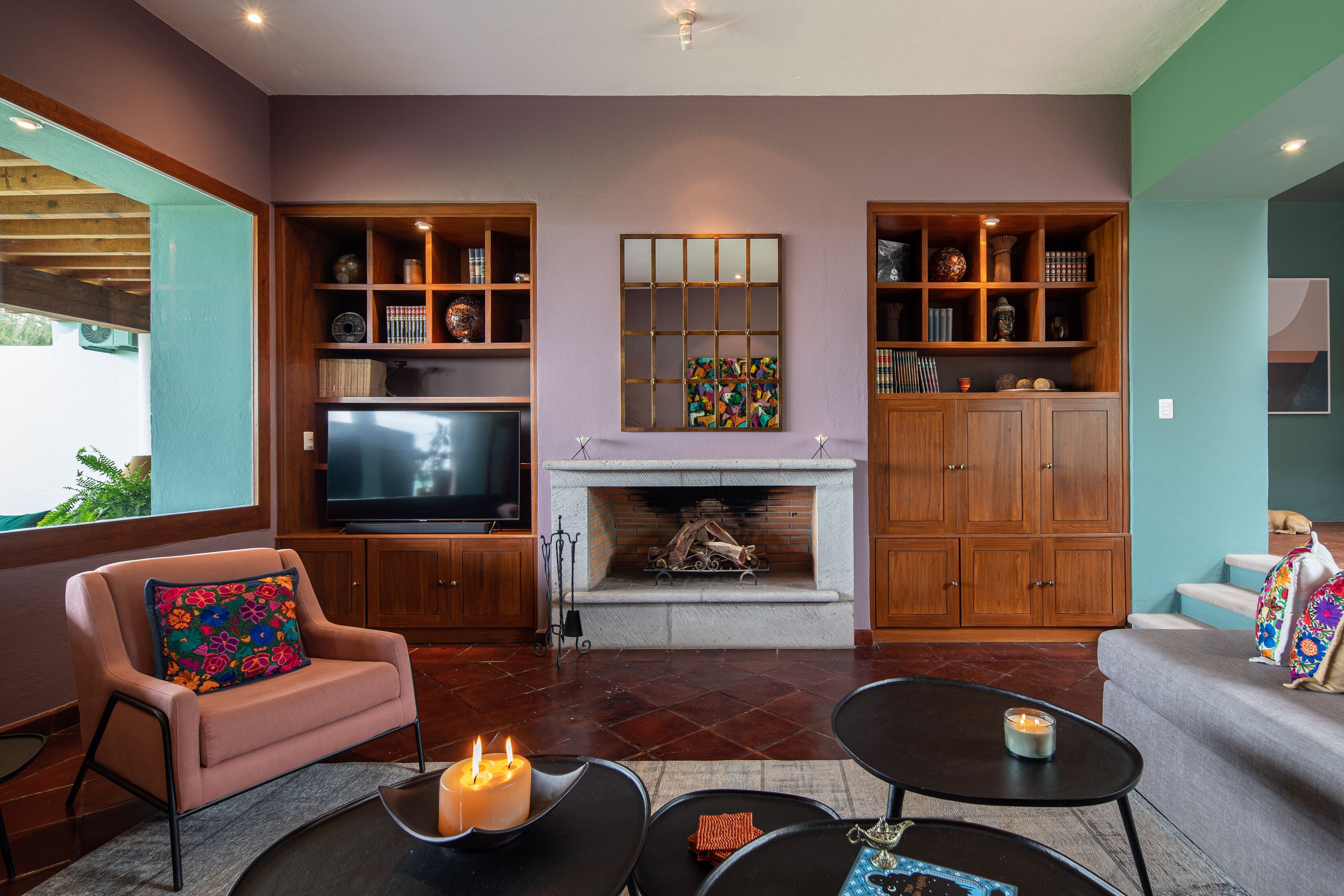 A living room with a fireplace, wooden shelving, a television, and a cozy seating area.