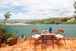 Eine Terrasse mit Tisch, Stühlen, Blumentöpfen und Blick auf die Stadt.