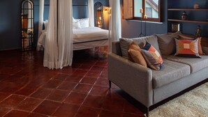 A bedroom with a four-poster bed, a sofa, a wooden ceiling, and a nightstand with a lamp. - Balcones 5BR Villa | Weddings | Stunning Views (San Miguel de Allende)