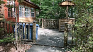 Een houten chalet met een veranda, een vogelhuisje en een houten omheining.