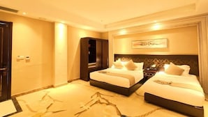 A hotel room with two beds, a nightstand, a mirror, and a painting on the wall.