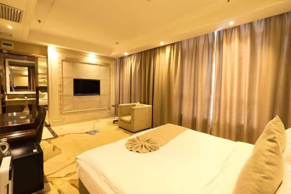 A hotel room with a bed, a desk, a chair, a television, and curtains.