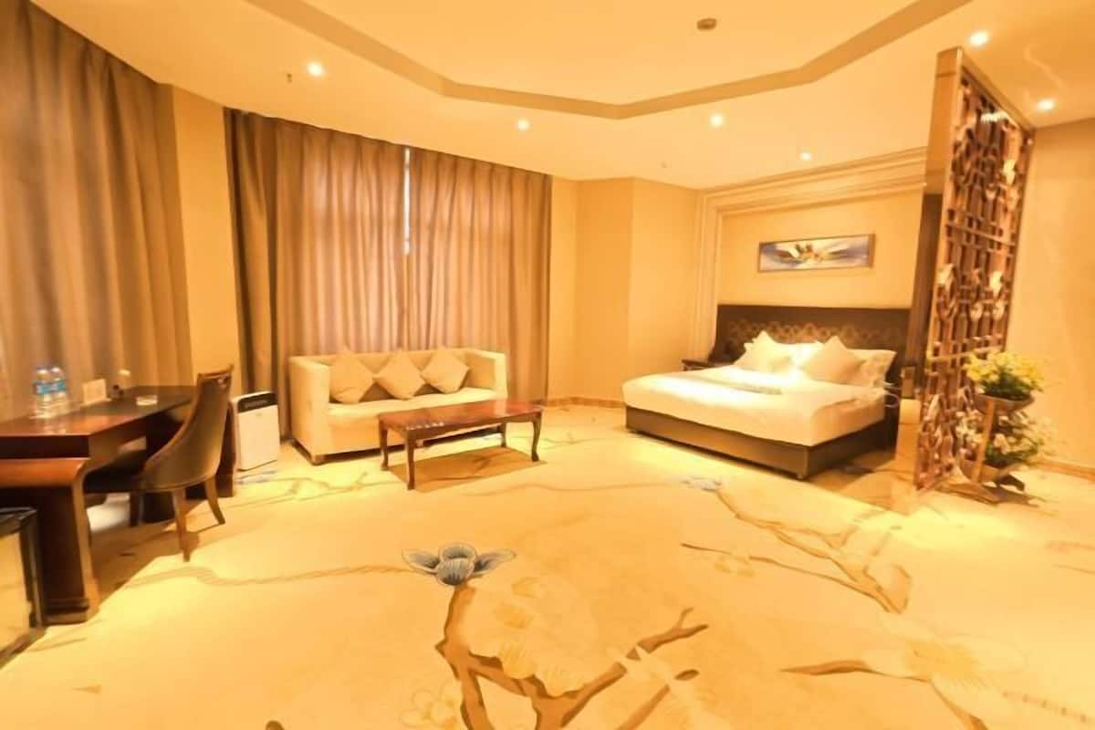 A hotel room with a bed, a sofa, a desk, and a chair.