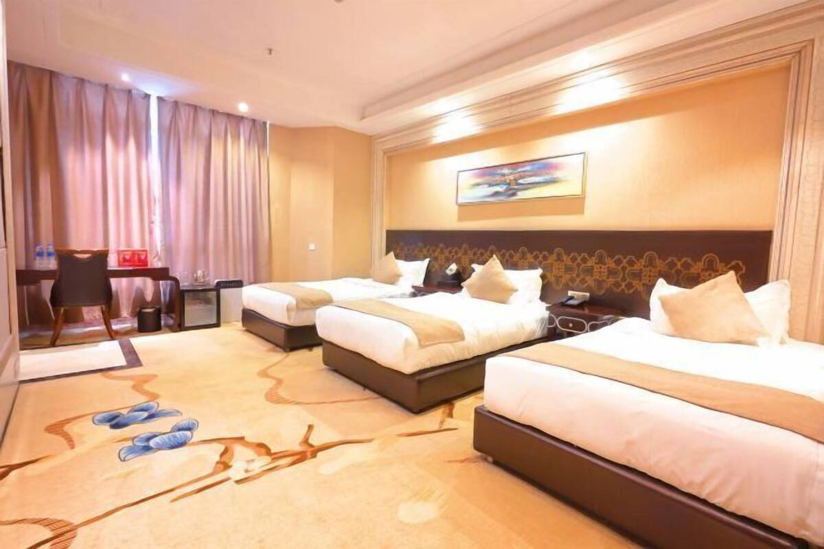 A hotel room with two beds, a desk, and a chair.