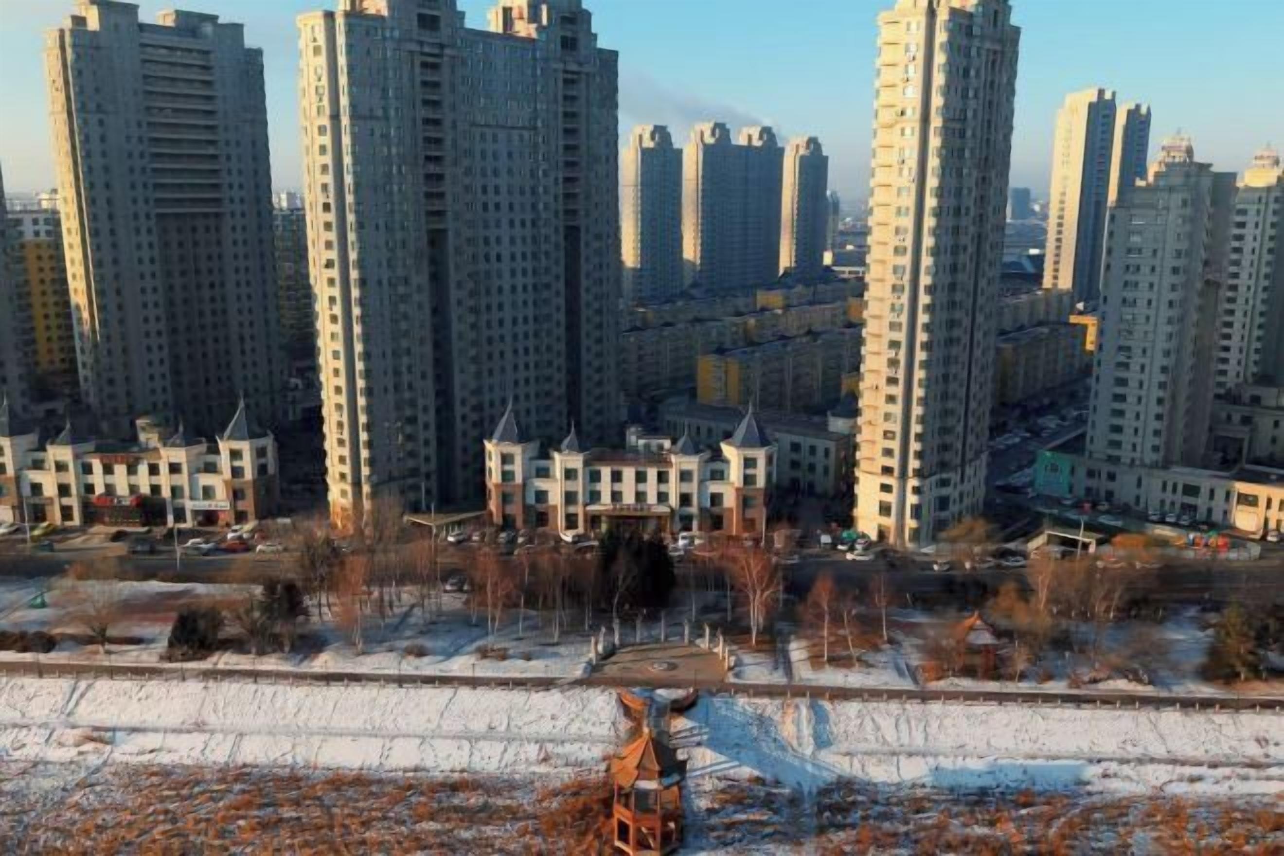 Un complejo residencial de edificios de gran altura, con varios edificios de apartamentos, una plaza central y suelo cubierto de nieve.